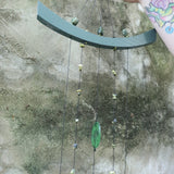 Someone holding the Chi Energy Jade Feng Shui Woodstock Wind Chime in front of a cement wall.