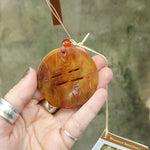 An up-close image of someone holding the amber ornament from the Woodstock Amber Wind Chime.
