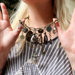 A woman wearing the Gypsy Junk Original-Gray 24" Necklace and holding it up to show individual charms.