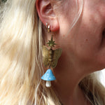 A woman wearing the blue Garden Goddess Mushroom Earrings.