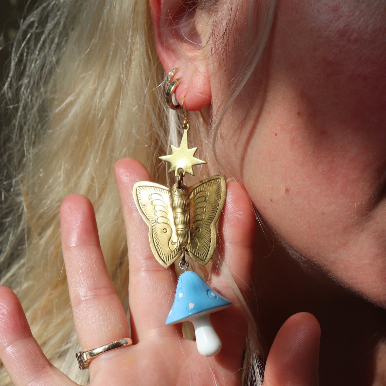 A woman wearing the blue Garden Goddess Mushroom Earrings.