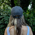 A woman wearing the Flower Garden Embroidered Adjustable Baseball Cap in front of greenery.