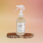 The Patchouli Vanilla Sea Salt Texturizing Hair Mist by Bohemian Rêves on an agate slice all on a pink and yellow background