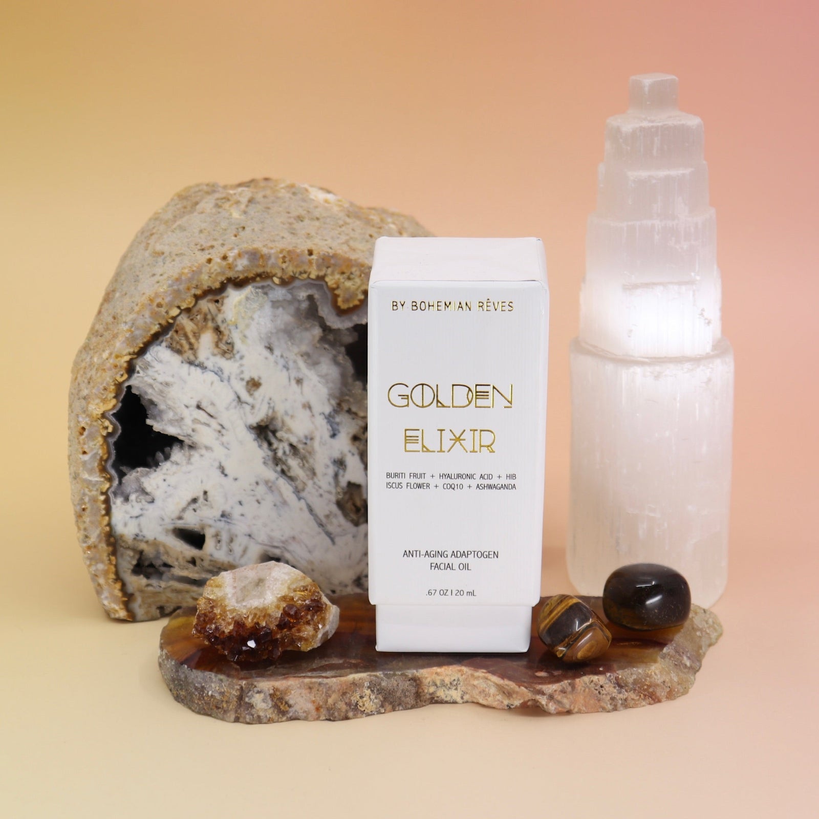 The Anti-Aging Elixir Face Oil from Bohemian Rêves on a slice of agate in front of a open geode and selenite tower, all on a pink and yellow background.
