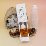 The Anti-Aging Elixir Face Oil from Bohemian Rêves on a slice of agate in front of a open geode and selenite tower, all on a pink and yellow background.