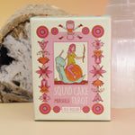 The Squid Cake Marseille Tarot Deck in front of a selenite tower and an agate slice all on a pink and yellow background.