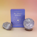 The Planet Grief Card Deck Bereavement Resource on a pink and yellow background, with two crystals in front of it.