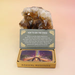 The Magical Messages from the Universe Affirmation + Divination Cards leaning against a citrine piece all on a pink and yellow background.