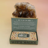 The Witch Magick Affirmation + Divination Cards against a citrine piece all on a pink and yellow background.