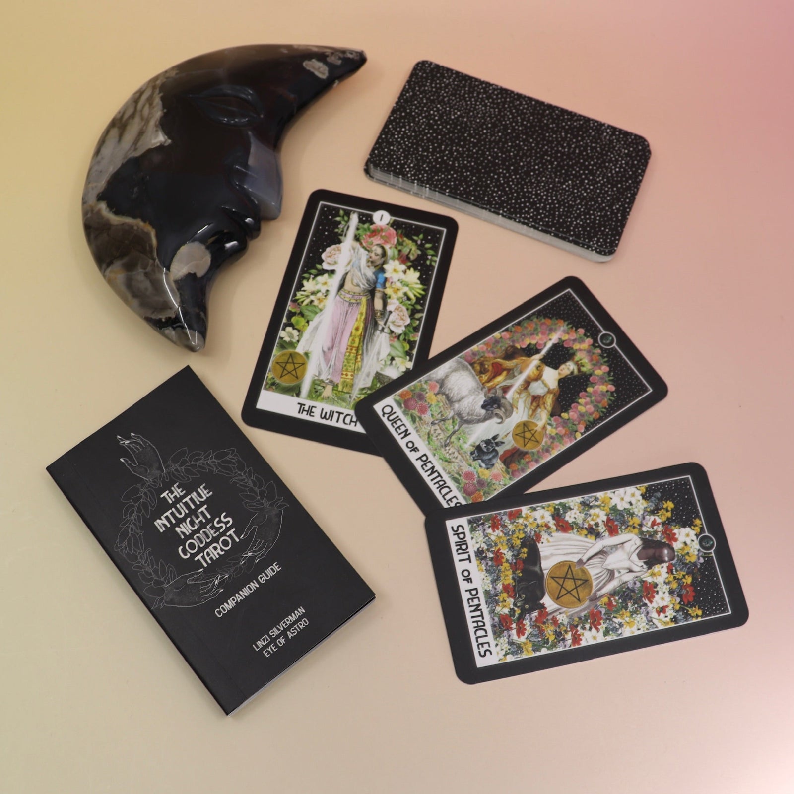 The contents of the Intuitive Night Goddess Tarot Deck on a pink and yellow background.