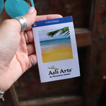 An up-close image of someone holding the tag of the Moon & Stars Capiz Chime in front of a wooden door.