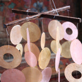 An up-close image of the Sunlit Bay Capiz Chime in front of a door.
