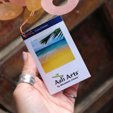 An image of someone holding the tag of the Sunlit Bay Capiz Chime in front of a door.