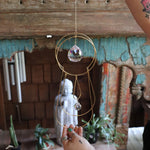 Someone holding the Prisma Hanging #43 Brass Suncatcher in front of a wooden altar.