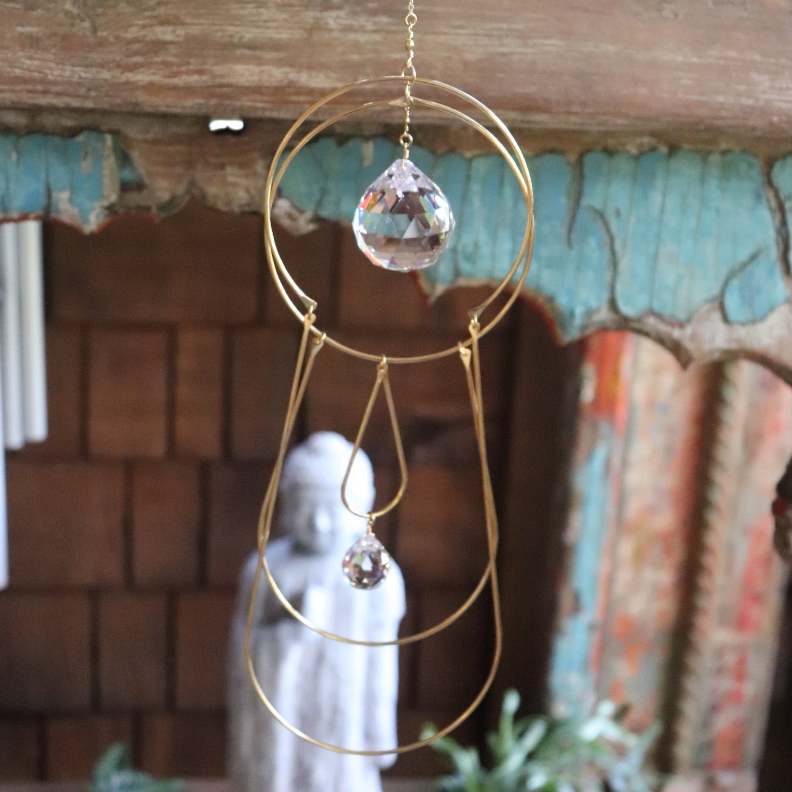 Someone holding the Prisma Hanging #43 Brass Suncatcher in front of a wooden altar.