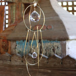 Someone holding the Prisma Hanging #43 Brass Suncatcher in front of a wooden altar.