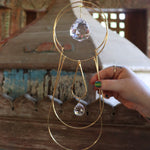 Someone holding the Prisma Hanging #43 Brass Suncatcher in front of a wooden altar.