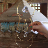 Someone holding the Prisma Hanging #43 Brass Suncatcher in front of a wooden altar.