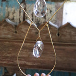 Someone holding the Prisma Hanging #42 Brass Geometrical Suncatcher in front of a wooden background.