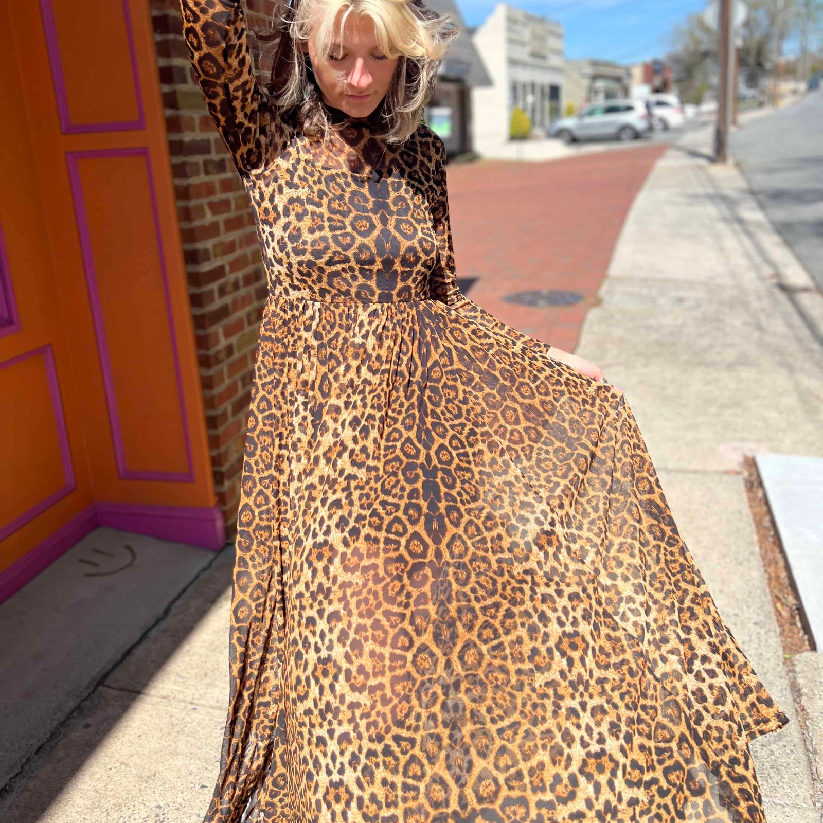 leopard mesh dress on model standing in front of orange and pink building with model looking down on dress
