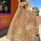 leopard mesh dress on model standing in front of orange and pink building holding skirt out looking down on dress