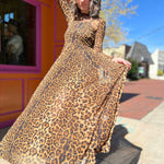 leopard mesh dress on model standing in front of orange and pink building holding skirt out to the left