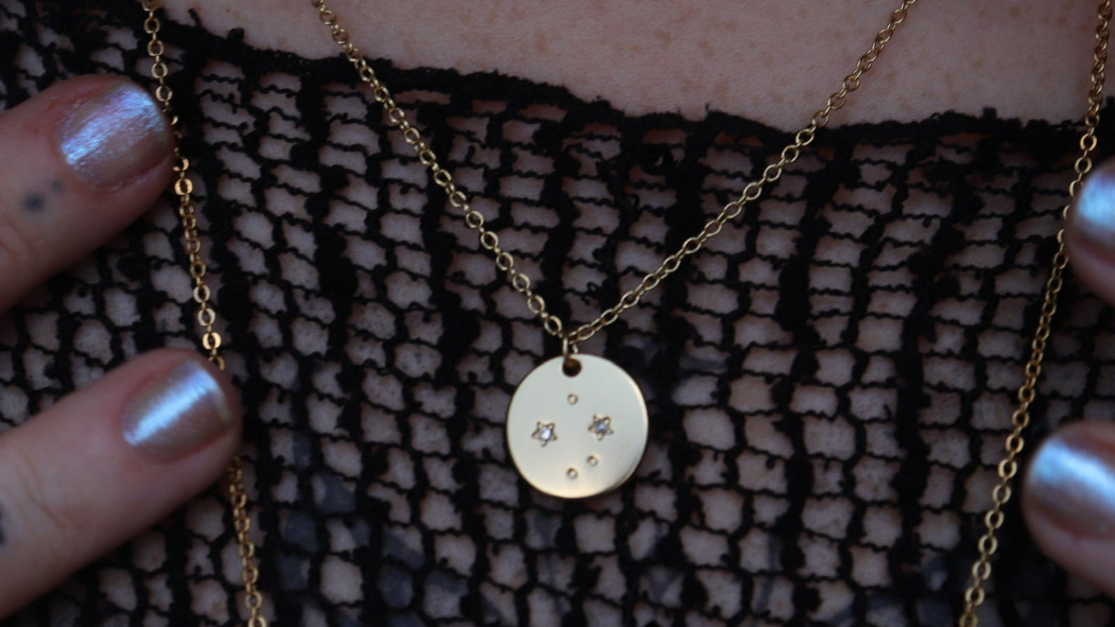 Someone wearing the Libra 14k Gold Dipped Nickel-Free Zodiac Necklace with a black net top.