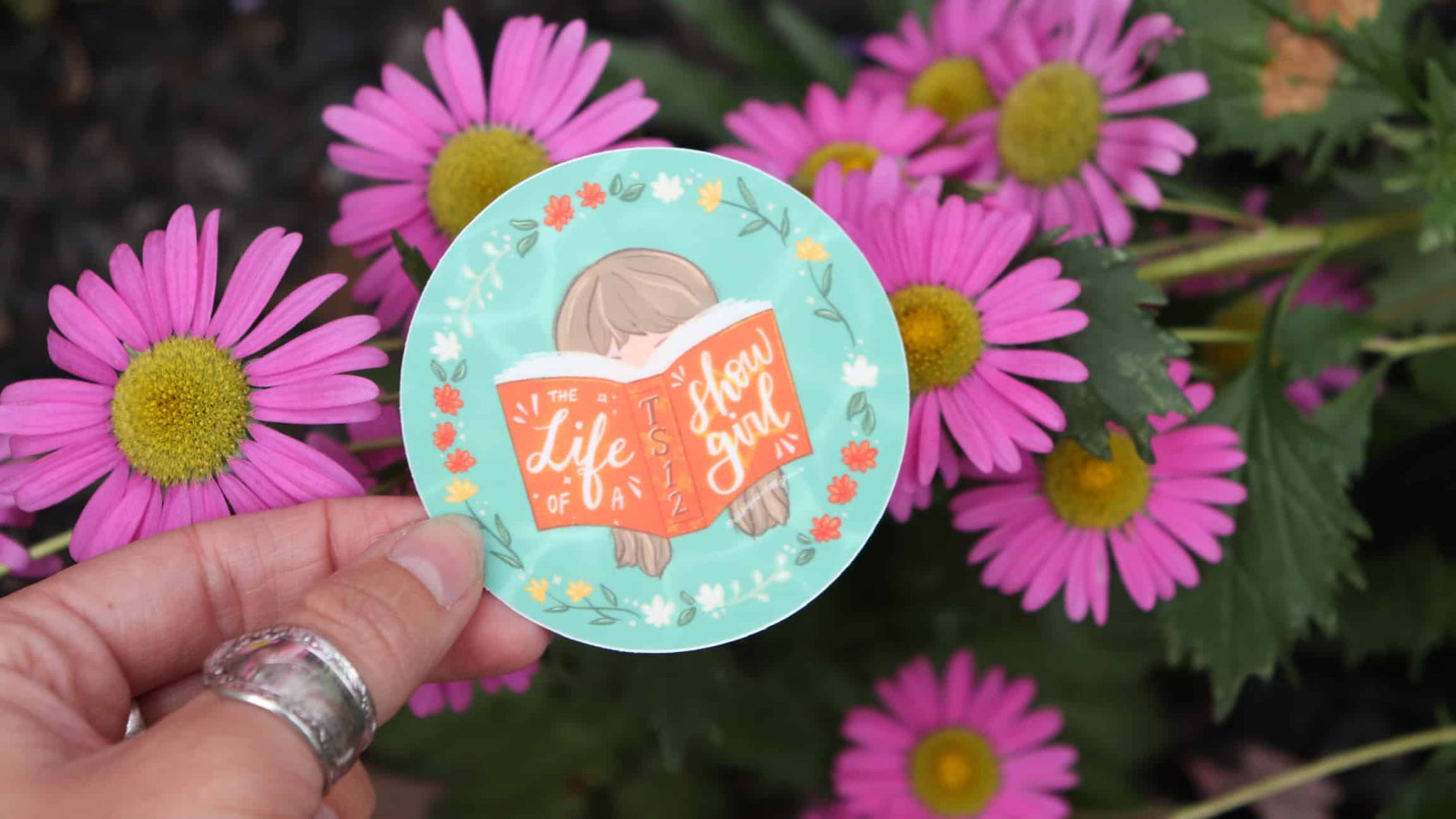 Taylor Swift Life of a Showgirl Sticker TS12 in front of pink flowers 