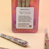 Holographic package of Manifest Magic Rollies with visible herbs inside, surrounded by individual rollies on a soft blush background