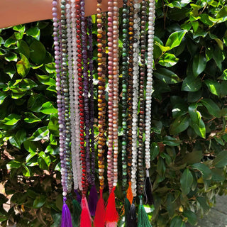 arm holding a variety of mala necklaces with green background
