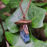 Crystal mushroom necklace displayed on green ivy leaves