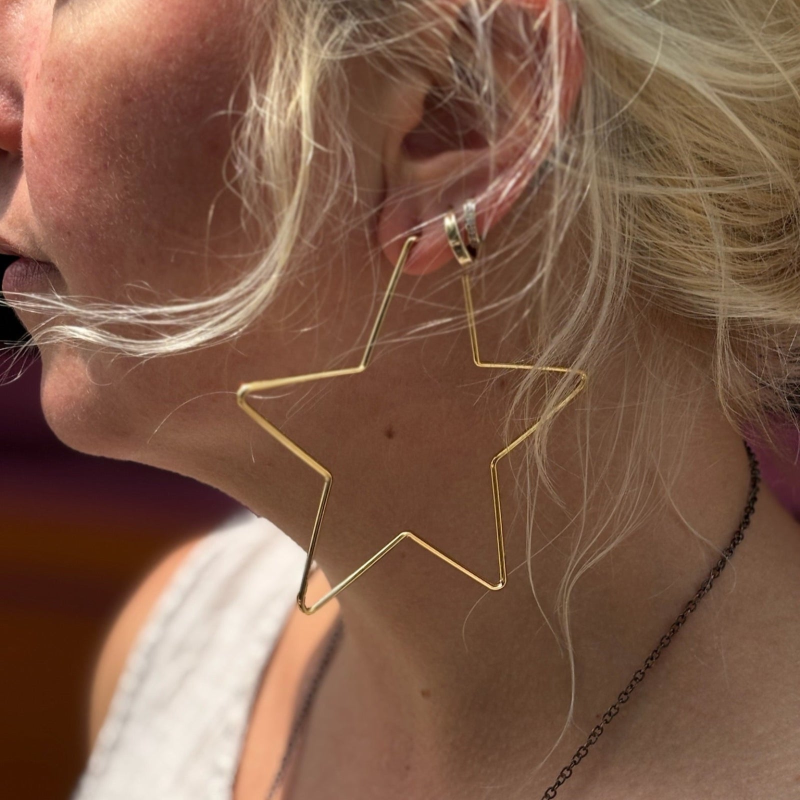 Close-up of 18K gold star hoop earring on ear