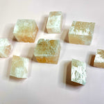 group of Iceland spar calcite cubes reflecting light naturally on pink background