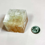 Optical calcite cube next to a quarter for size comparison