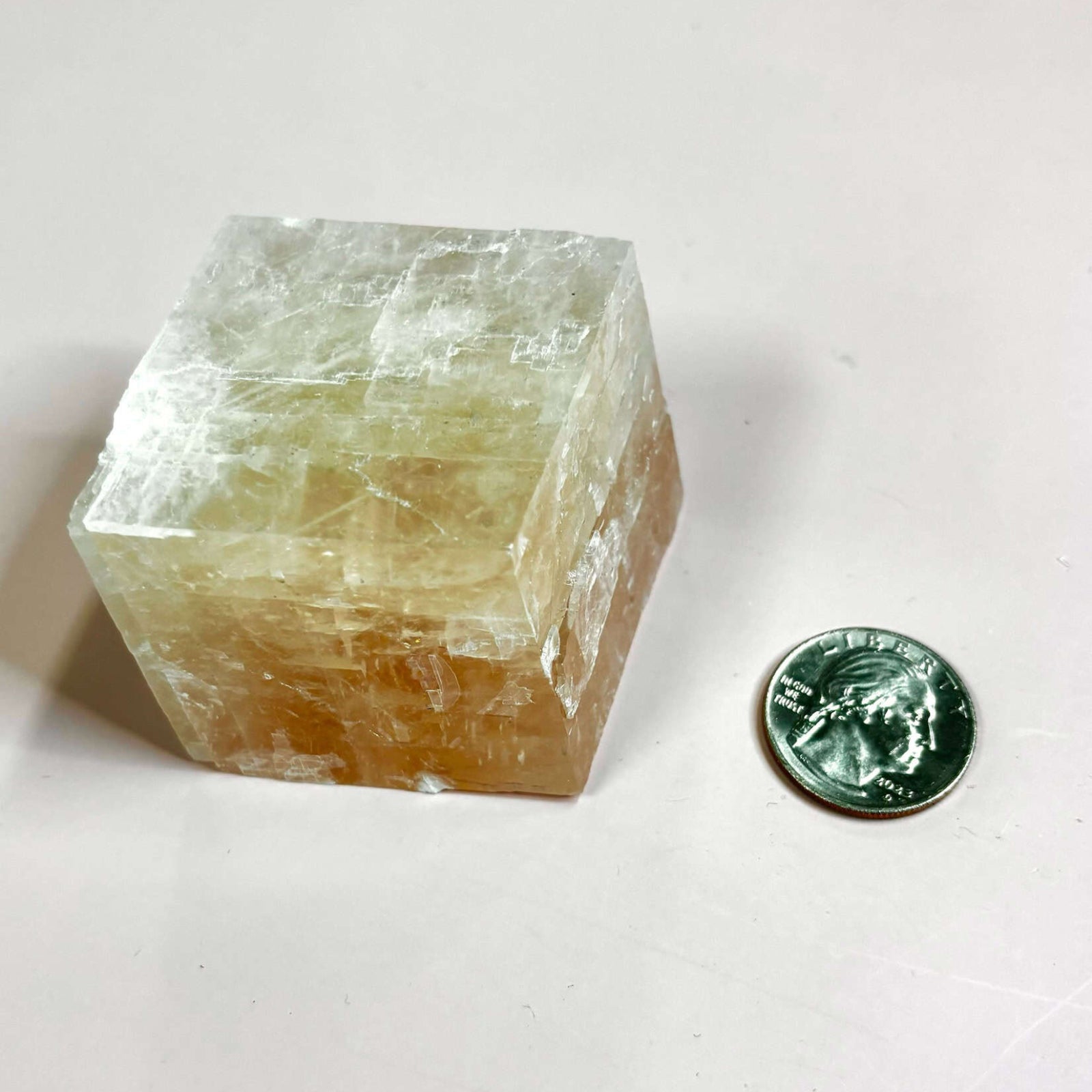 Optical calcite cube next to a quarter for size comparison