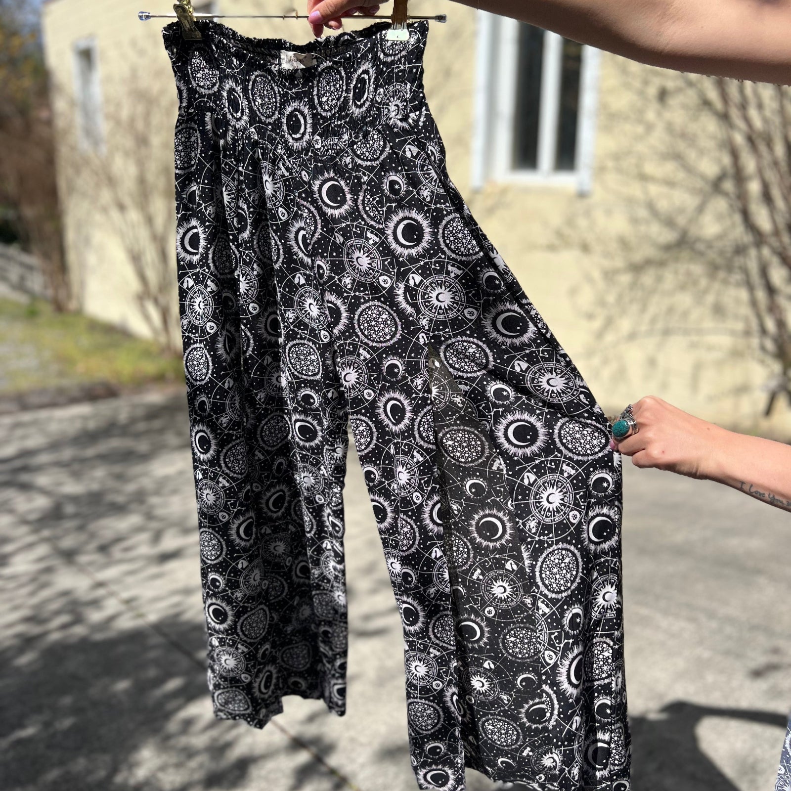Someone holding the black Celestial Faux Wrap Pants.