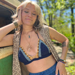 A woman wearing the navy Festive Crochet Top: One Size with blue pants and a long patterned vest. 