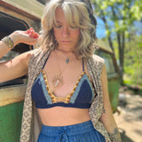 A woman wearing the navy Festive Crochet Top: One Size with blue pants and a long patterned vest. 