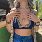 A woman wearing the navy Festive Crochet Top: One Size with blue pants and a long patterned vest. 