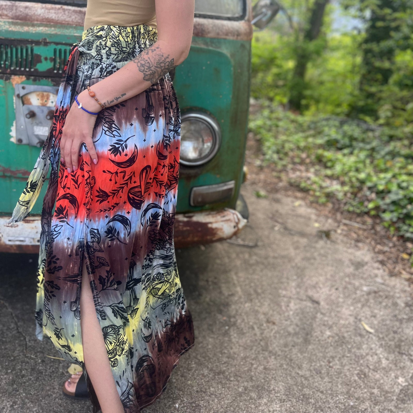 Someone wearing the Mushroom Tie-Dye Maxi Skirt in front of an old teal Volkswagen bus.