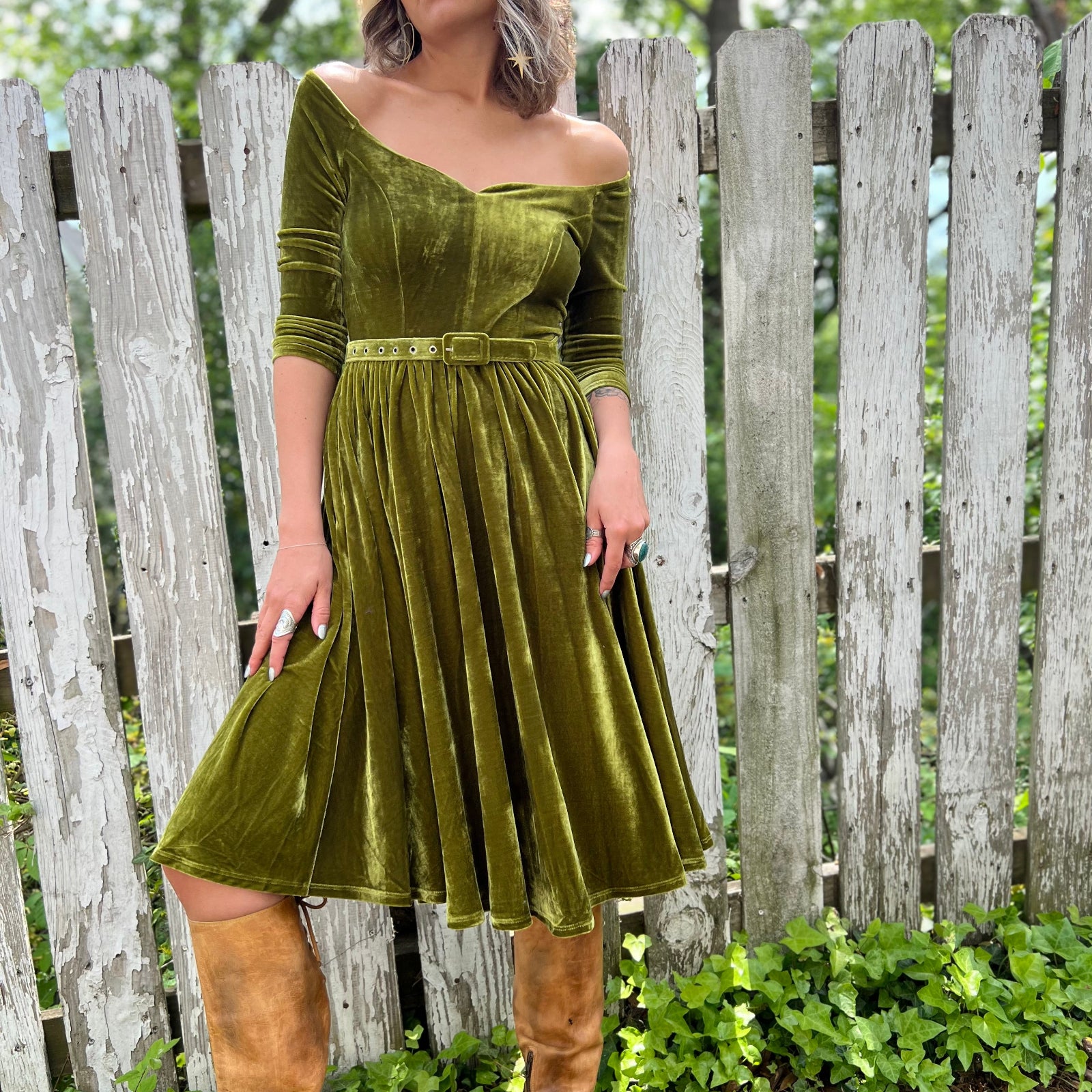 A woman wearing the 1950s Chartreuse Velvet Sweetheart Swing Dress in front of a wooden fence.