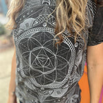 A woman wearing the Gray Mandala Stonewashed Cotton T-shirt with jeans in front an orange and pink wall.