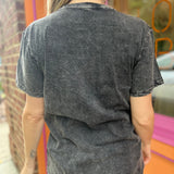 A woman wearing the Gray Mandala Stonewashed Cotton T-shirt with jeans in front an orange and pink wall.