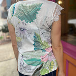 A woman wearing the Butterfly Lace Embroidered Trim Short Sleeve Top in front of an orange and pink wall.