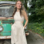 A woman wearing the cream Solid Linen Cut-Out Midi Dress in front of a vintage teal Volkswagen bus.