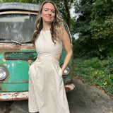 A woman wearing the cream Solid Linen Cut-Out Midi Dress in front of a vintage teal Volkswagen bus.