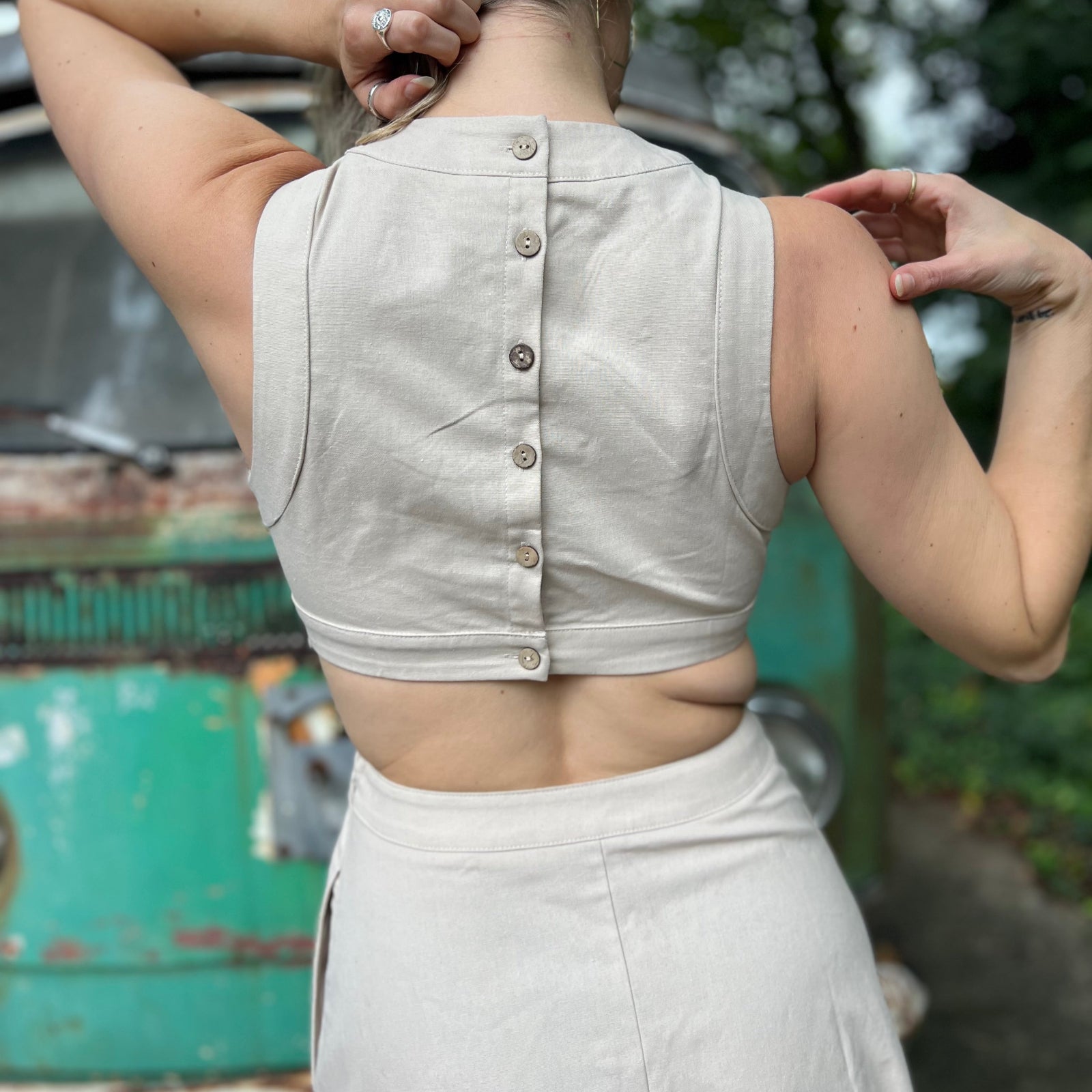 A woman wearing the cream Solid Linen Cut-Out Midi Dress in front of a vintage teal Volkswagen bus.