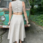 A woman wearing the cream Solid Linen Cut-Out Midi Dress in front of a vintage teal Volkswagen bus.