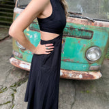 A woman wearing the black Solid Linen Cut-Out Midi Dress in front of a vintage teal Volkswagen bus.
