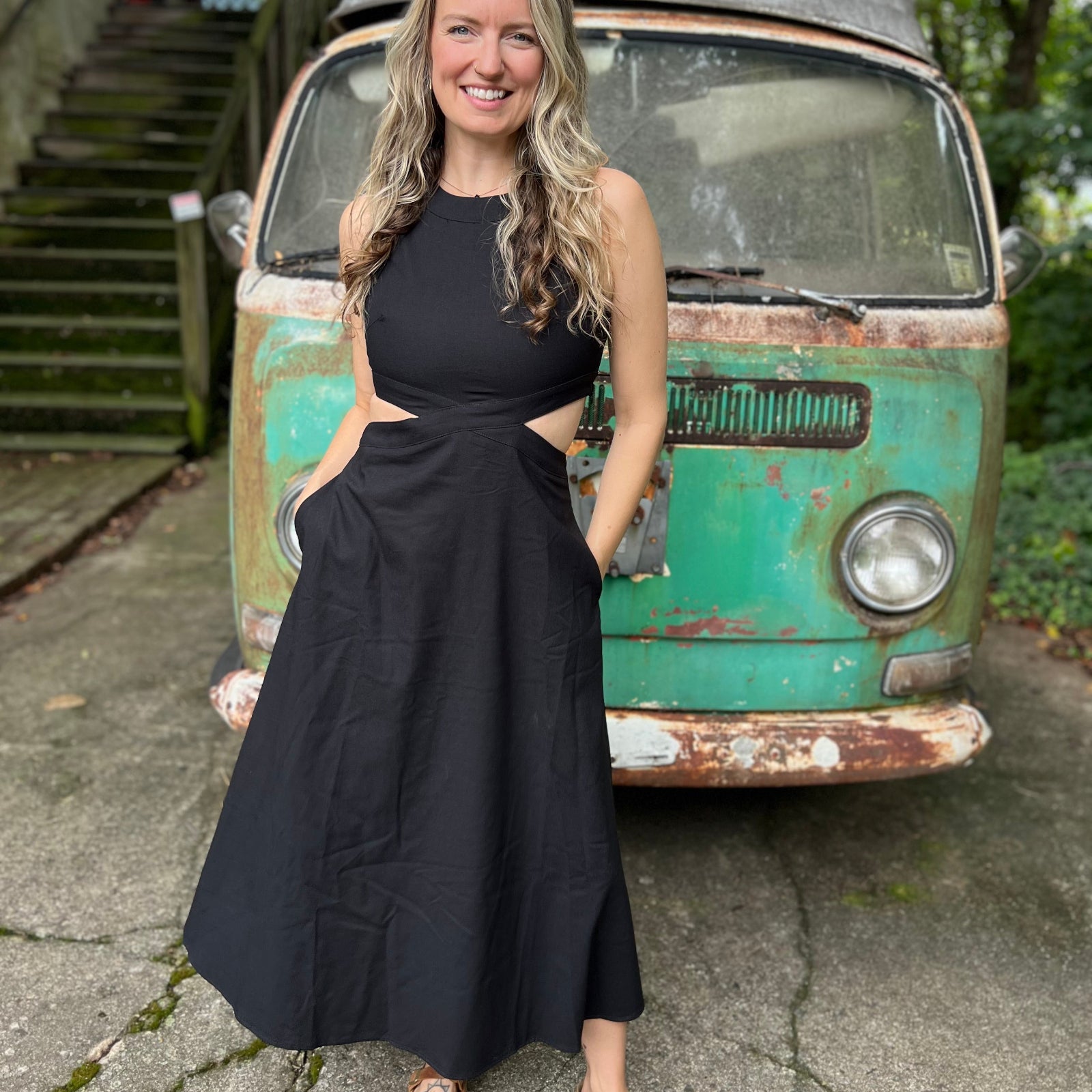 A woman wearing the black Solid Linen Cut-Out Midi Dress in front of a vintage teal Volkswagen bus.